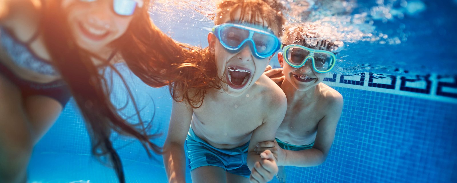 Kinder im Schwimmbad beim tauchen mit Taucherbrille haben Spaß.