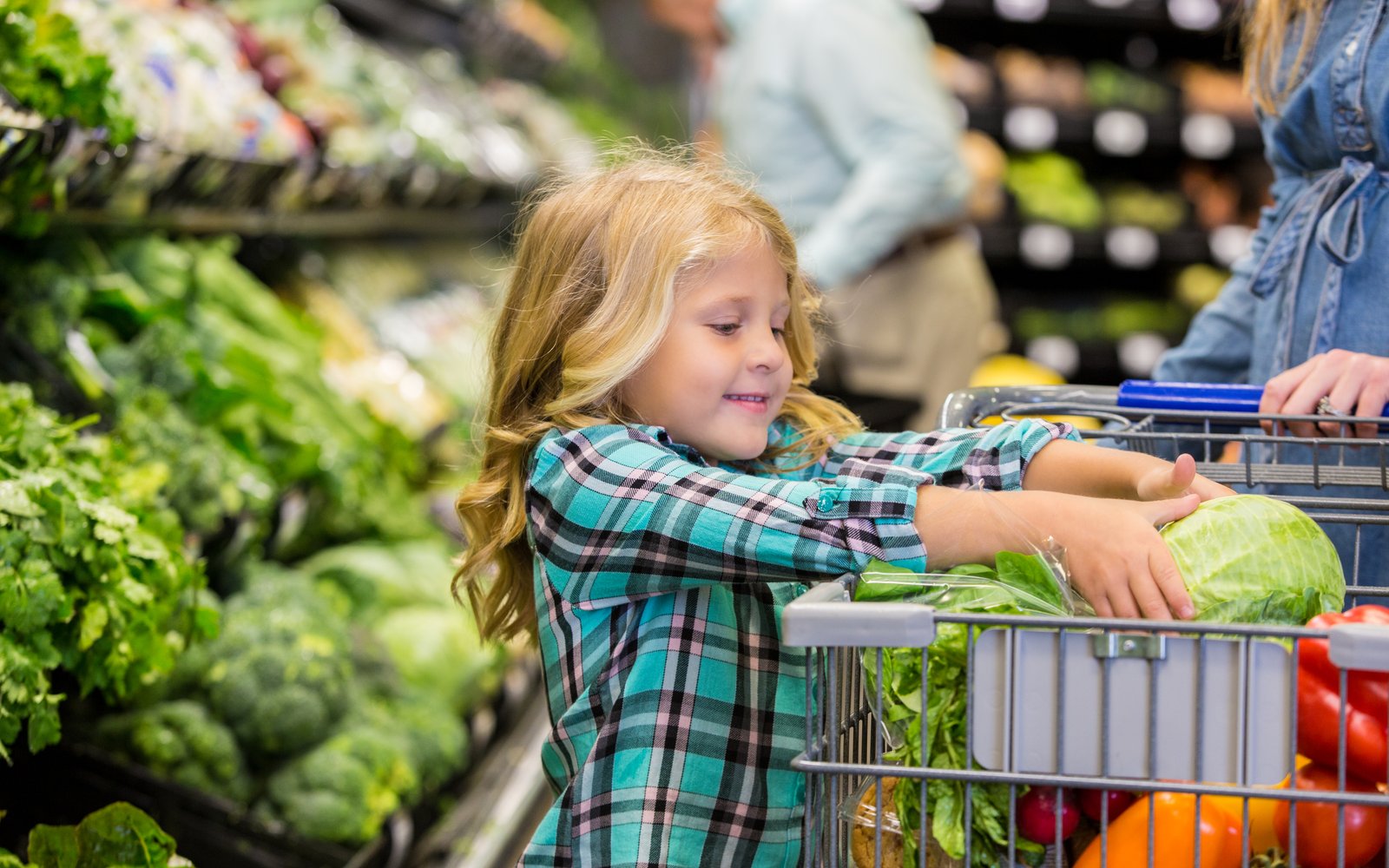 Freundliches Mädchen packt Lebensmittel in den Einkaufswagen in einem Edeka Supermarkt auf Sylt
