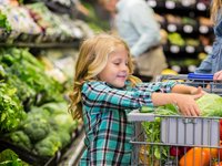 Freundliches Mädchen packt Lebensmittel in den Einkaufswagen in einem Edeka Supermarkt auf Sylt